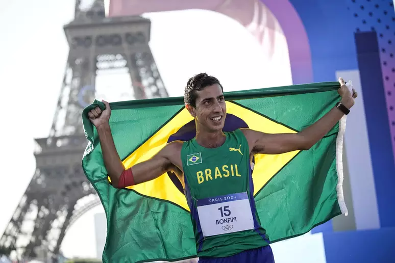 Caio Bonfim eguendo a bandeira do Brasil em Paris proximo a Torre Eiffel 