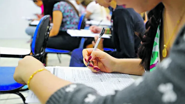 Estudante em sala de aula escrevendo em um caderno