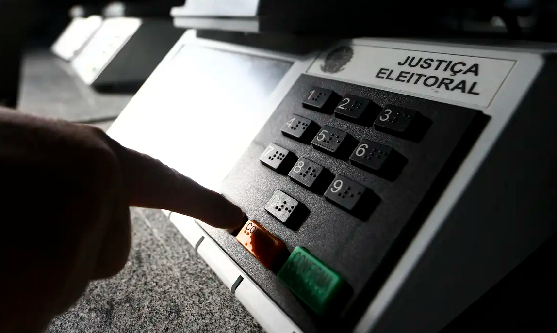 Uma pessoa apertando o dedo na urna eletrônica