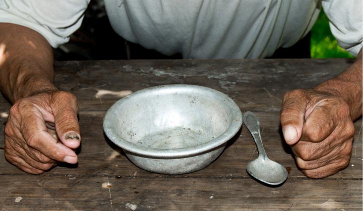 prato vazio e uma colher do lado e as mãos de um homem