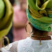 Mulher negra de costas usando um turbante, argolas e um cordão